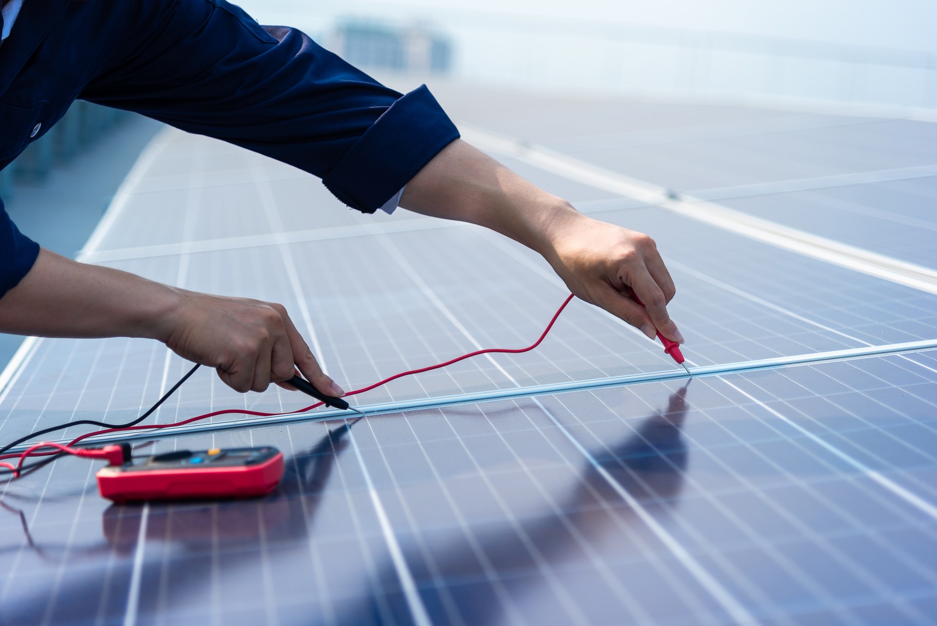 Close up hands of the engineers are using electrical measuring instruments on the solar cell plan.